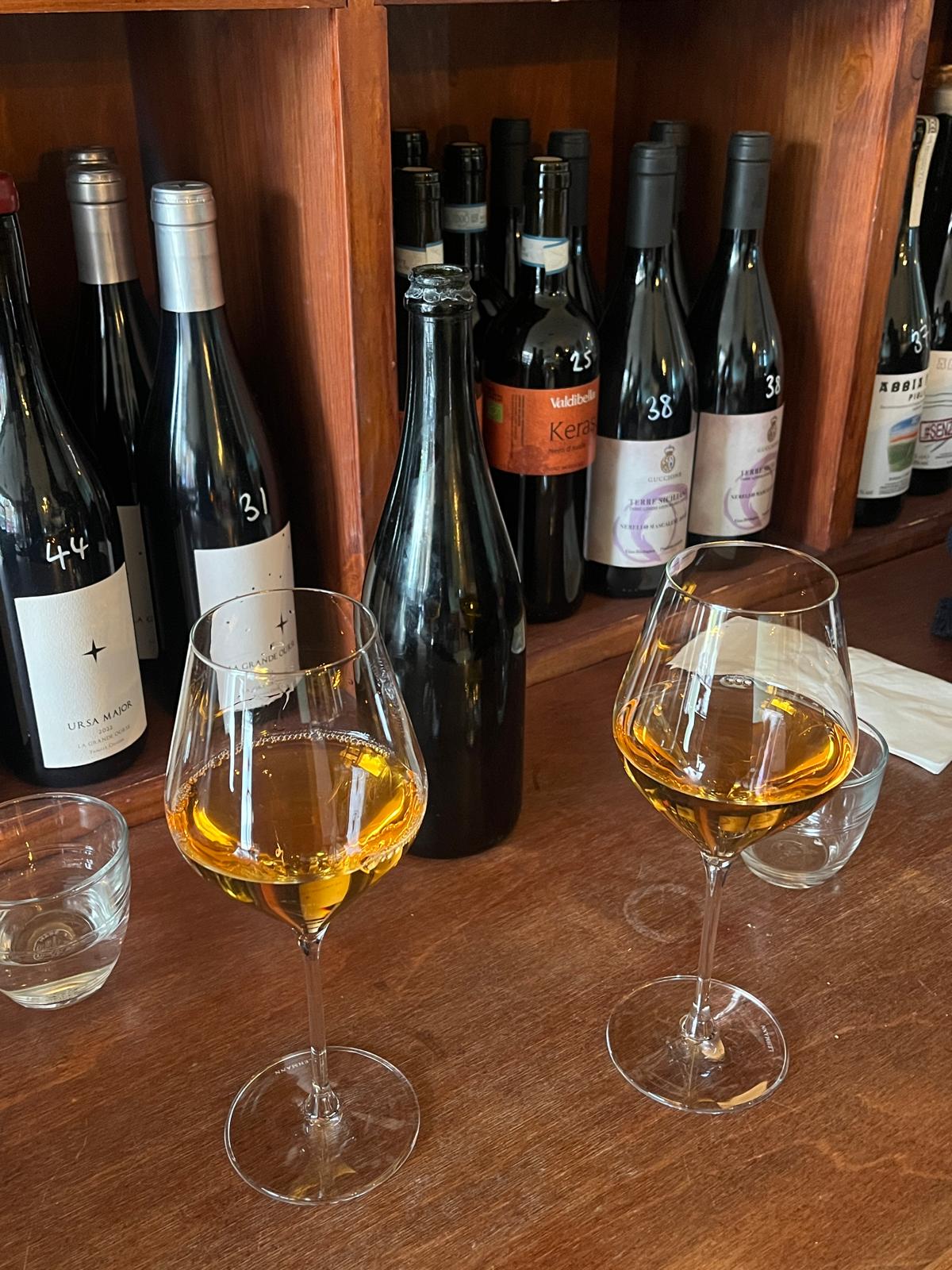 Orange wine in glasses with natural wine bottles behind