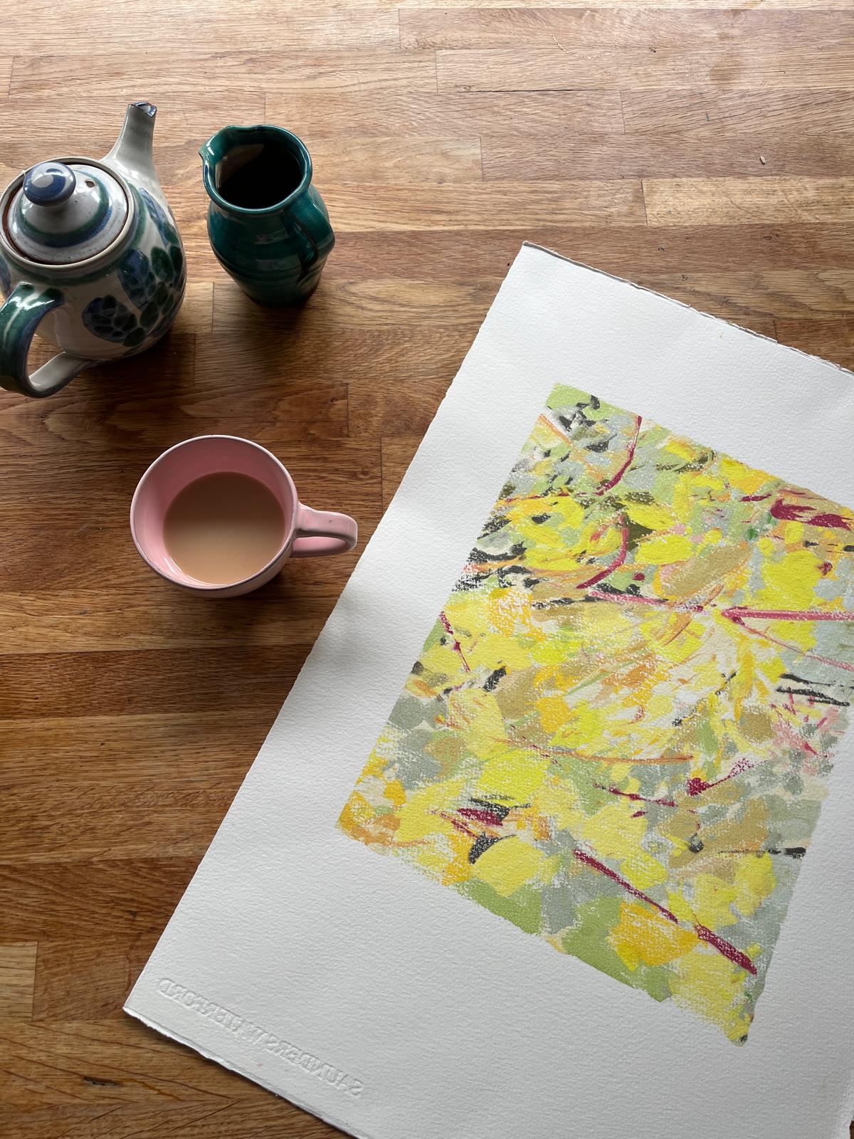 Abstract painting beside a teapot and a pink mug of tea