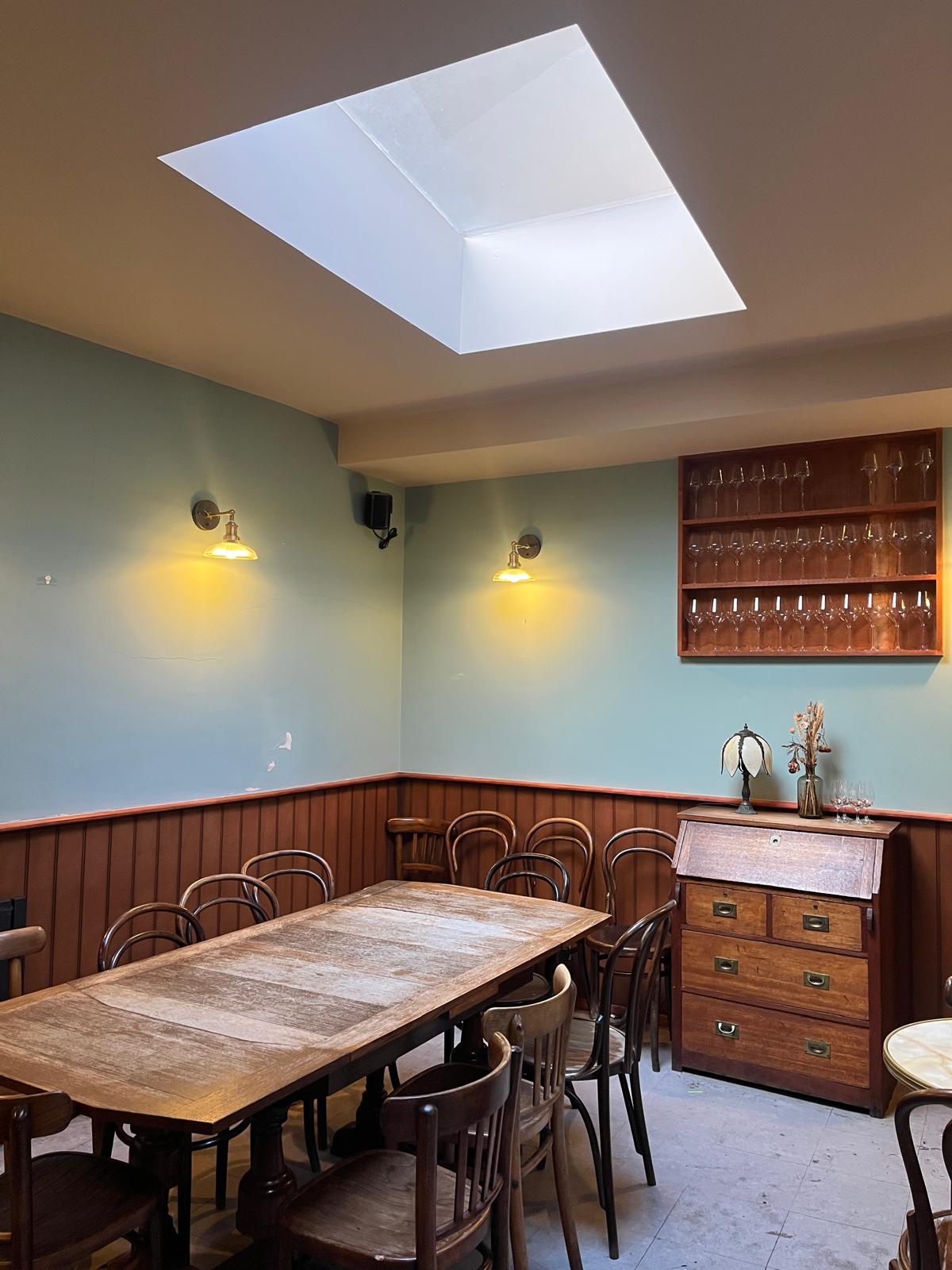 A cosy event room with wooden tables and wine glasses on the wall