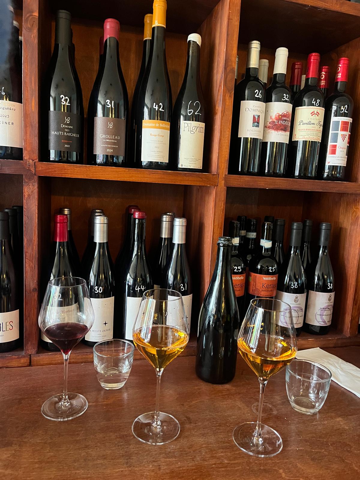 Natural wine glasses with bottles on the shelves behind